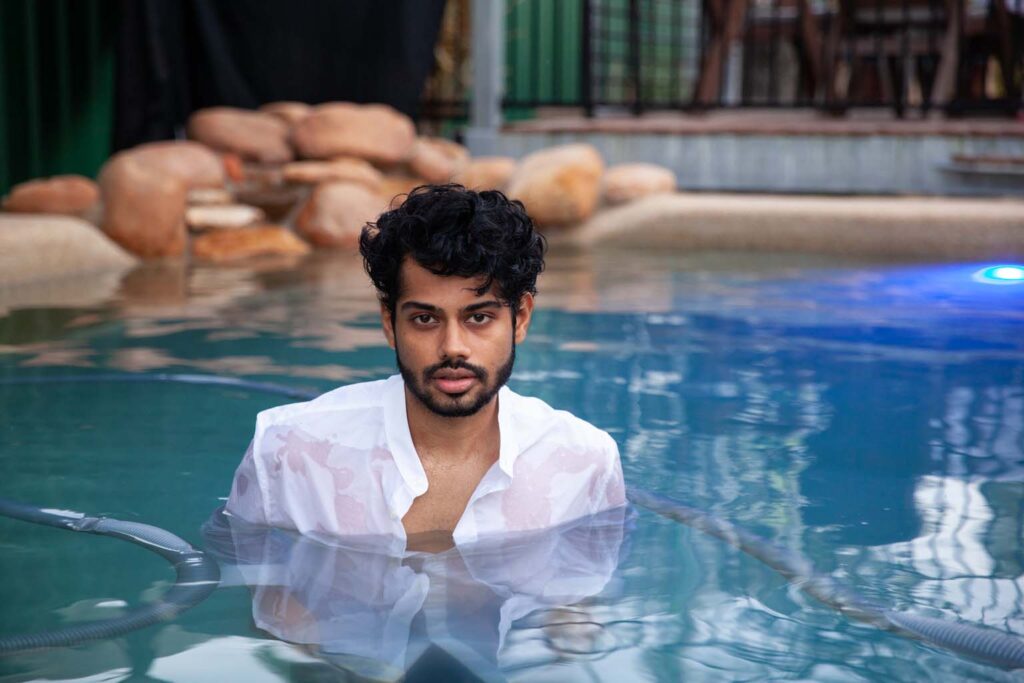 Young man in pool wearing white shirt