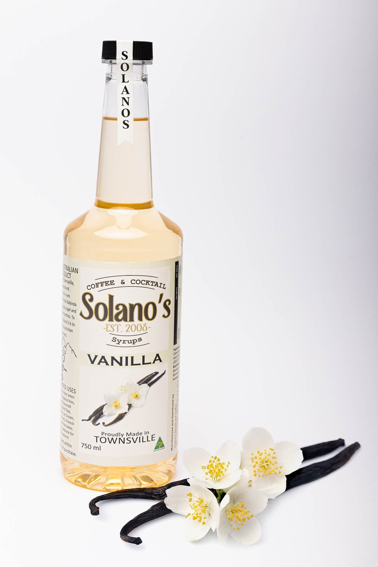 product photography of vanilla coffee syrup with vanilla pods and flowers