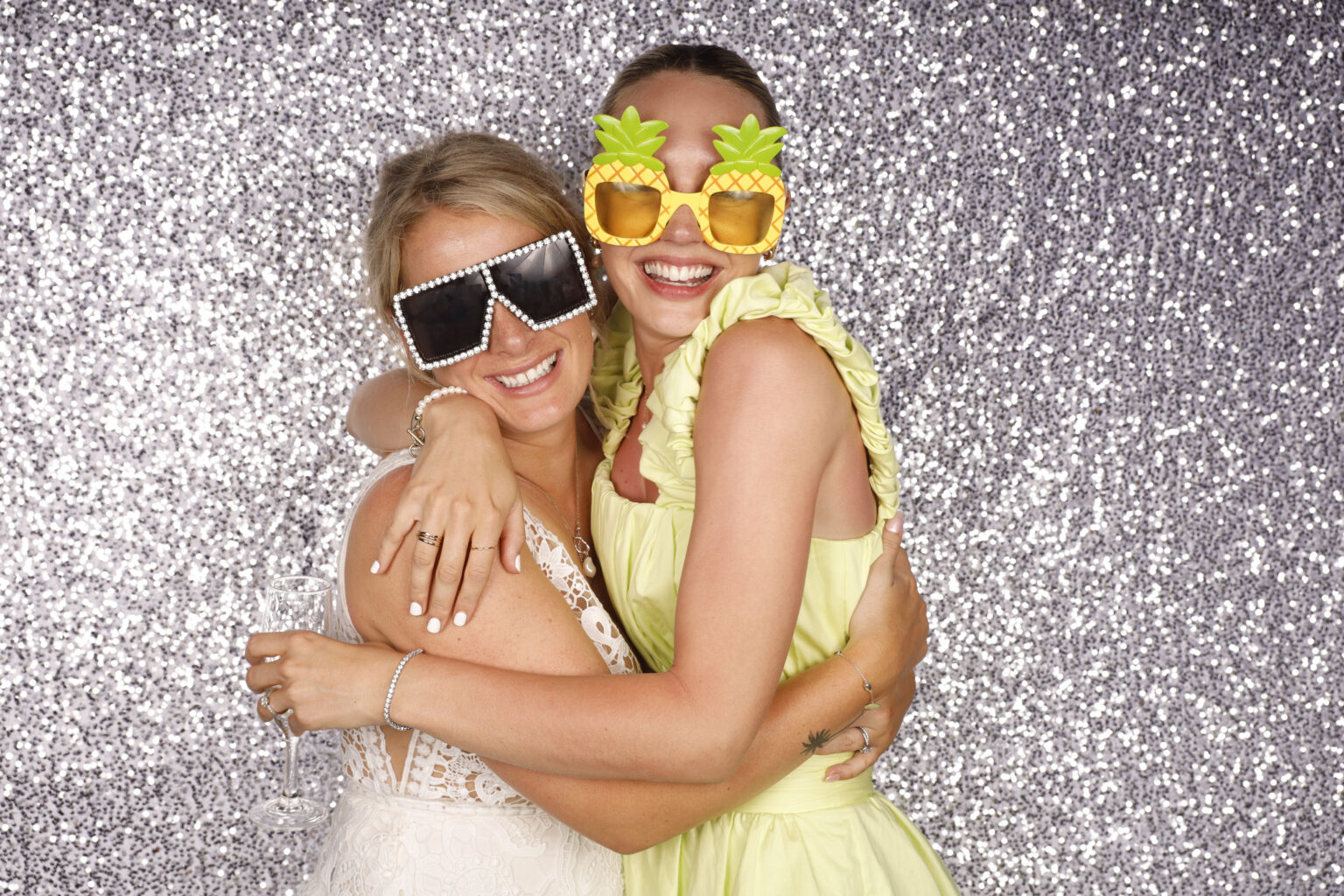 Two ladies in photo booth with props hugging with smiles
